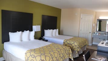 Une chambre d’hôtel avec deux lits, un bureau, une chaise, un miroir et une salle de bain équipée d’un lavabo et de toilettes.