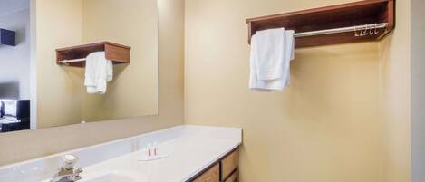 Un baño con un lavamanos blanco, un espejo con iluminación y un perchero para toallas.