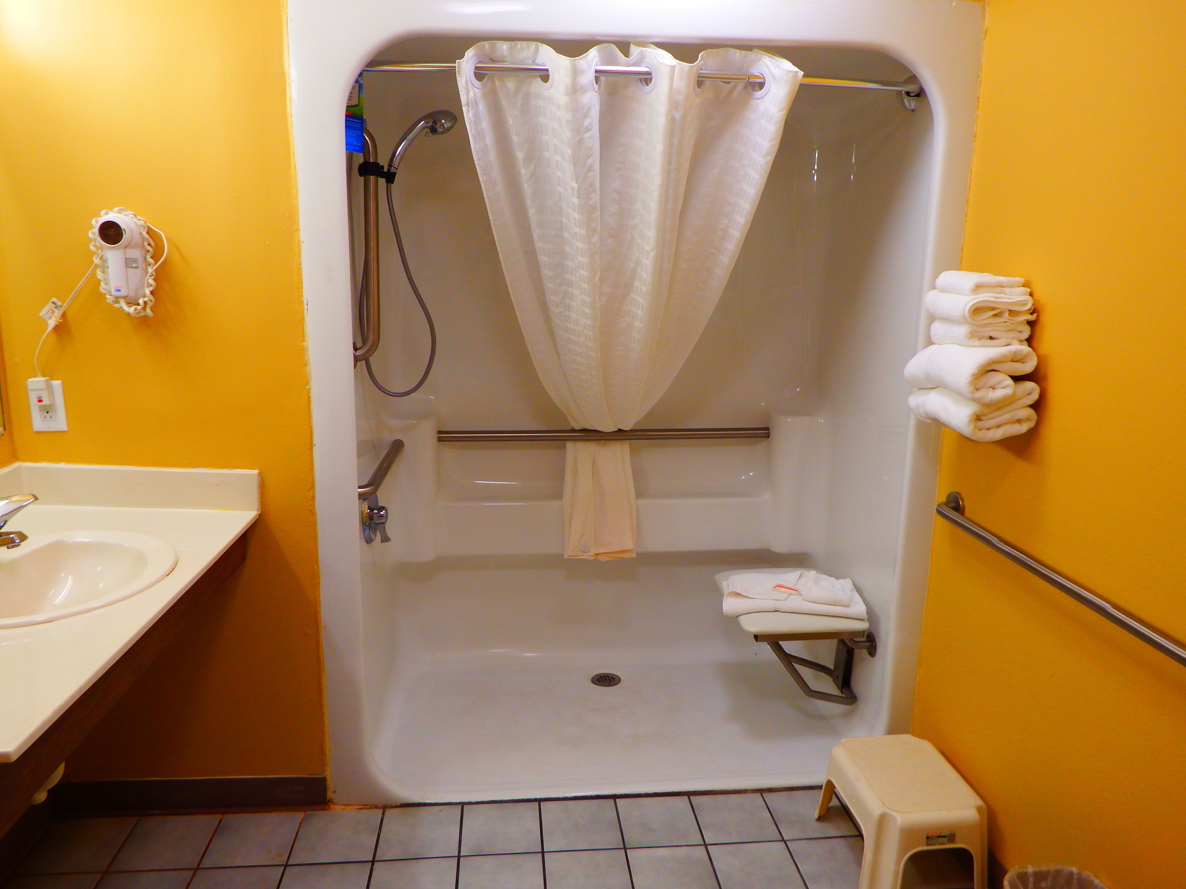 A bathroom with a white bathtub, a shower, a sink, and a toilet.