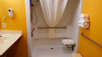 Une salle de bain avec une baignoire blanche, une douche, un lavabo et des toilettes.