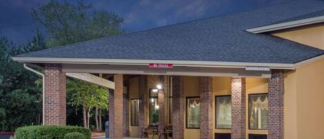 A motel with a covered parking area, a 'No Trucks' sign, and a brick facade.