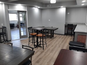 Una cocina moderna con zona de comedor, que incluye una mesa y sillas de madera, una isla de cocina y una pared decorativa de ladrillo.