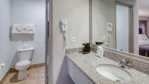 A bathroom with a toilet, a sink, a mirror, and a hairdryer. - SureStay by Best Western Salt Lake City Downtown (Salt Lake City)