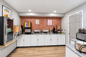 A kitchen with a brick wall, white cabinets, a coffee machine, and a toaster. - SureStay by Best Western Salt Lake City Downtown (Salt Lake City)
