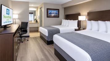 A hotel room with two beds, a desk, a chair, a television, and a framed picture on the wall.