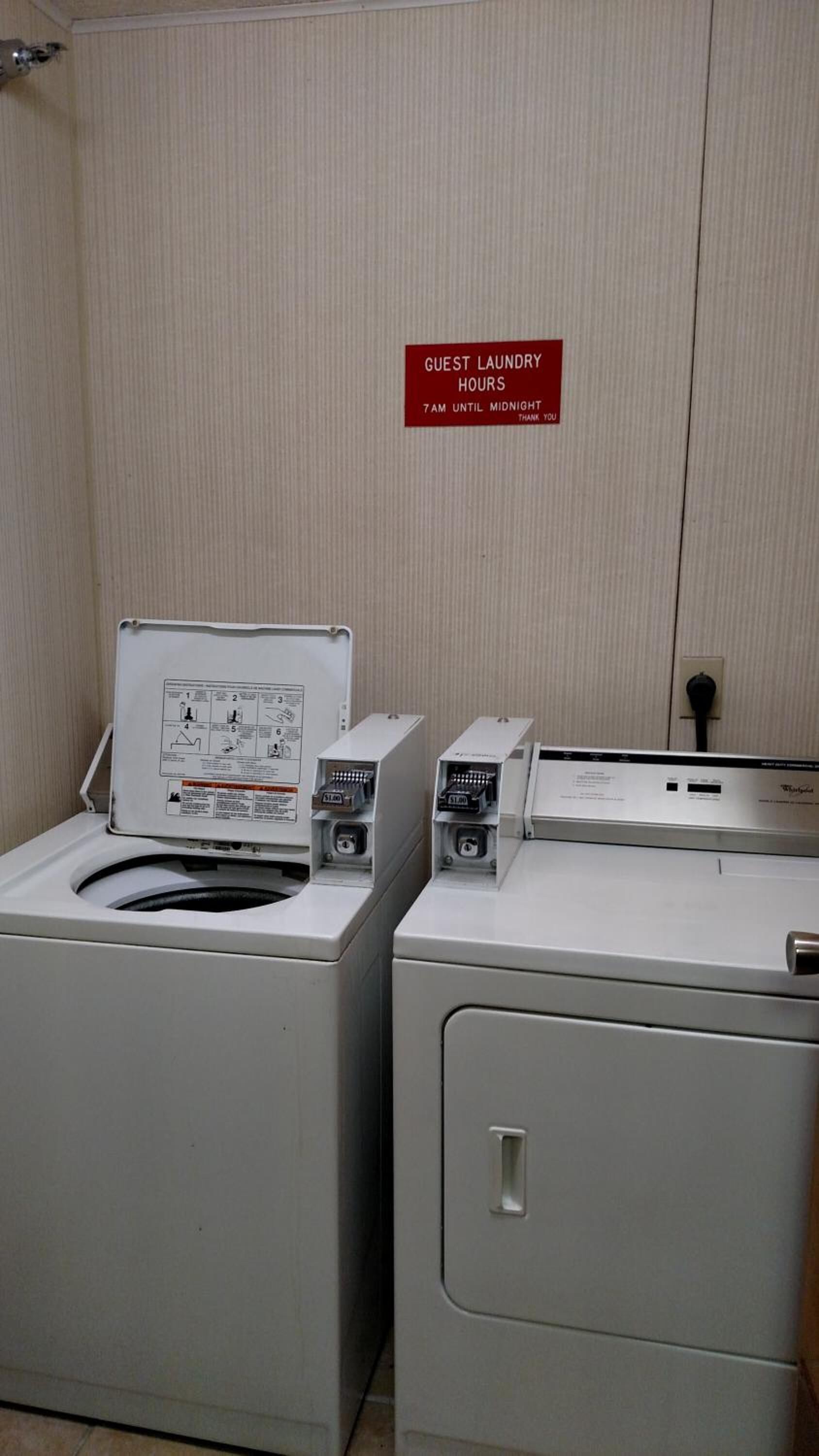 A laundry area with two washing machines and a sign indicating guest laundry hours from 7 AM until midnight.