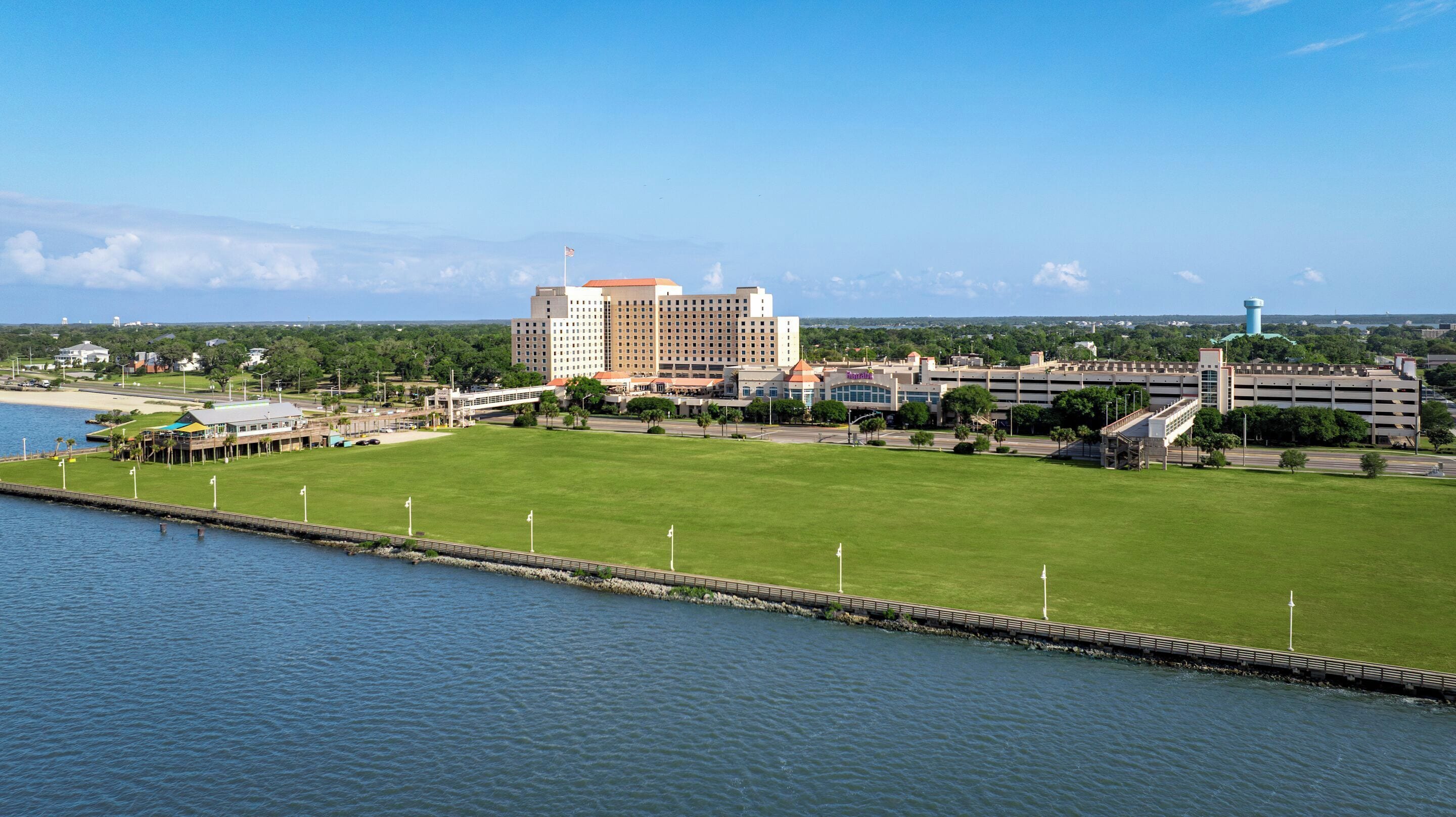 A large hotel with multiple buildings, a grassy area, and a waterfront.