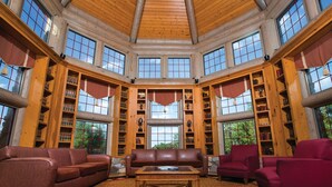 A spacious library with a high ceiling, large windows, and multiple bookshelves filled with books and trophies. - Harrah's Gulf Coast Hotel & Casino - A Caesars Rewards Destination (Biloxi)