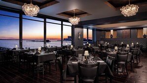 A restaurant with tables set for dining, large windows with a view of the water, and a chandelier. - Harrah's Gulf Coast Hotel & Casino - A Caesars Rewards Destination (Biloxi)
