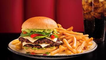 A burger with fries and a soda on a plate.