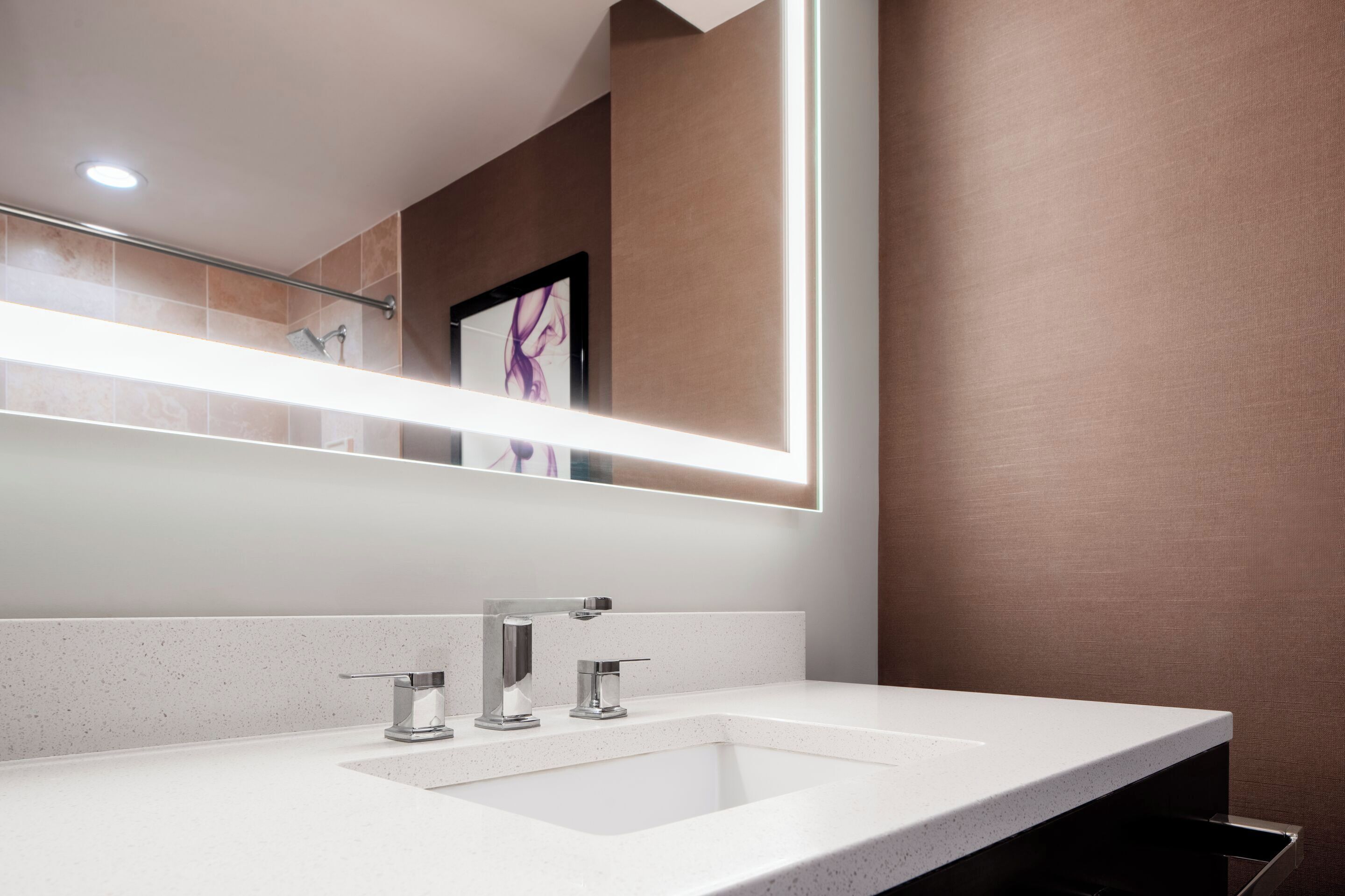 Un baño moderno con un espejo grande, un lavamanos blanco y una zona de ducha.