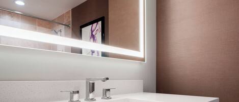 Un baño moderno con un espejo grande, un lavamanos blanco y una zona de ducha.