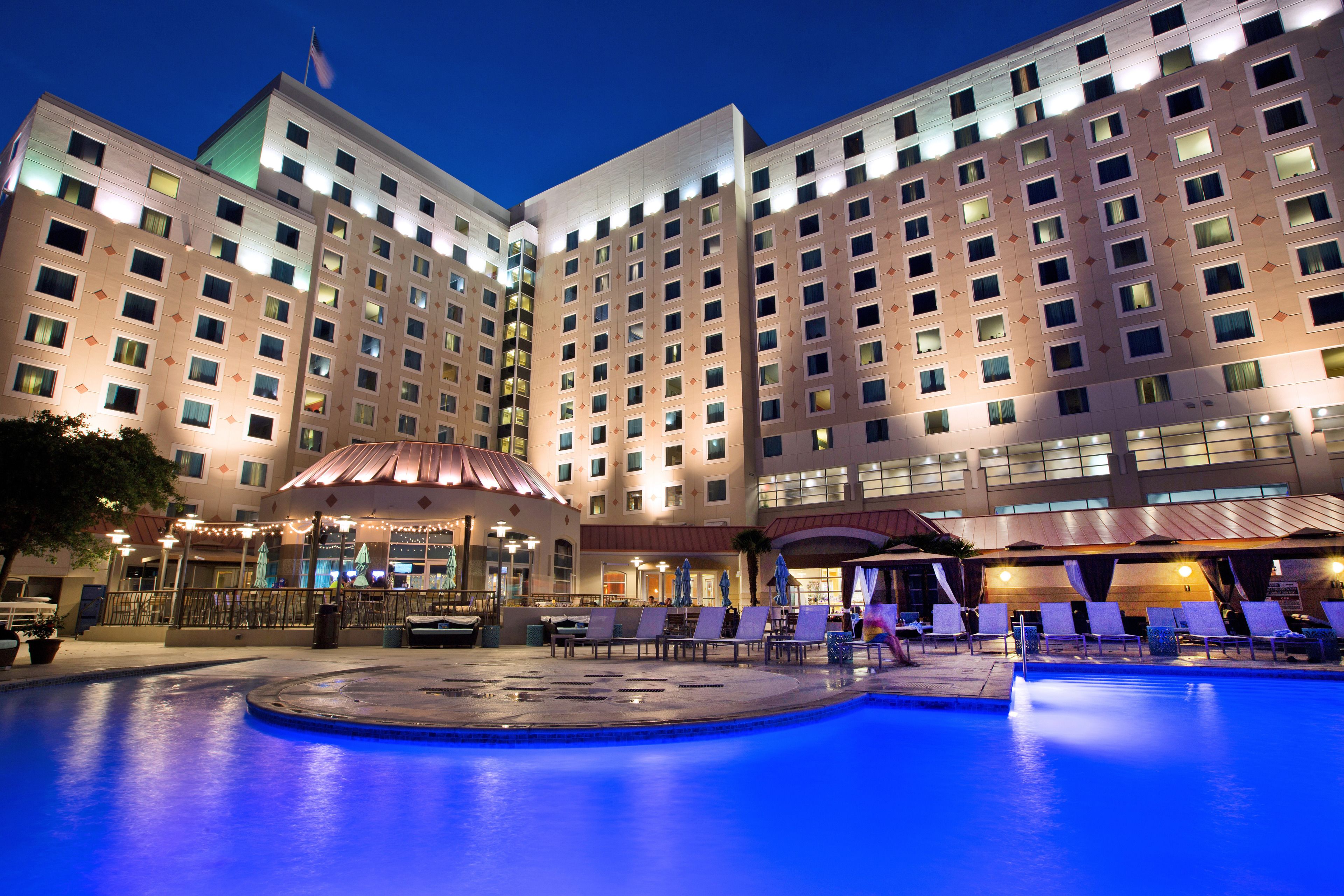 Un hotel con una piscina grande, varias zonas de descanso y un área de estar techada.