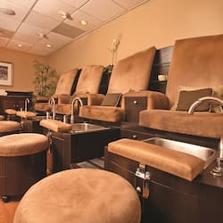 Relax in a serene spa room with massage chairs, footrests, and a large cabinet with a mirror.