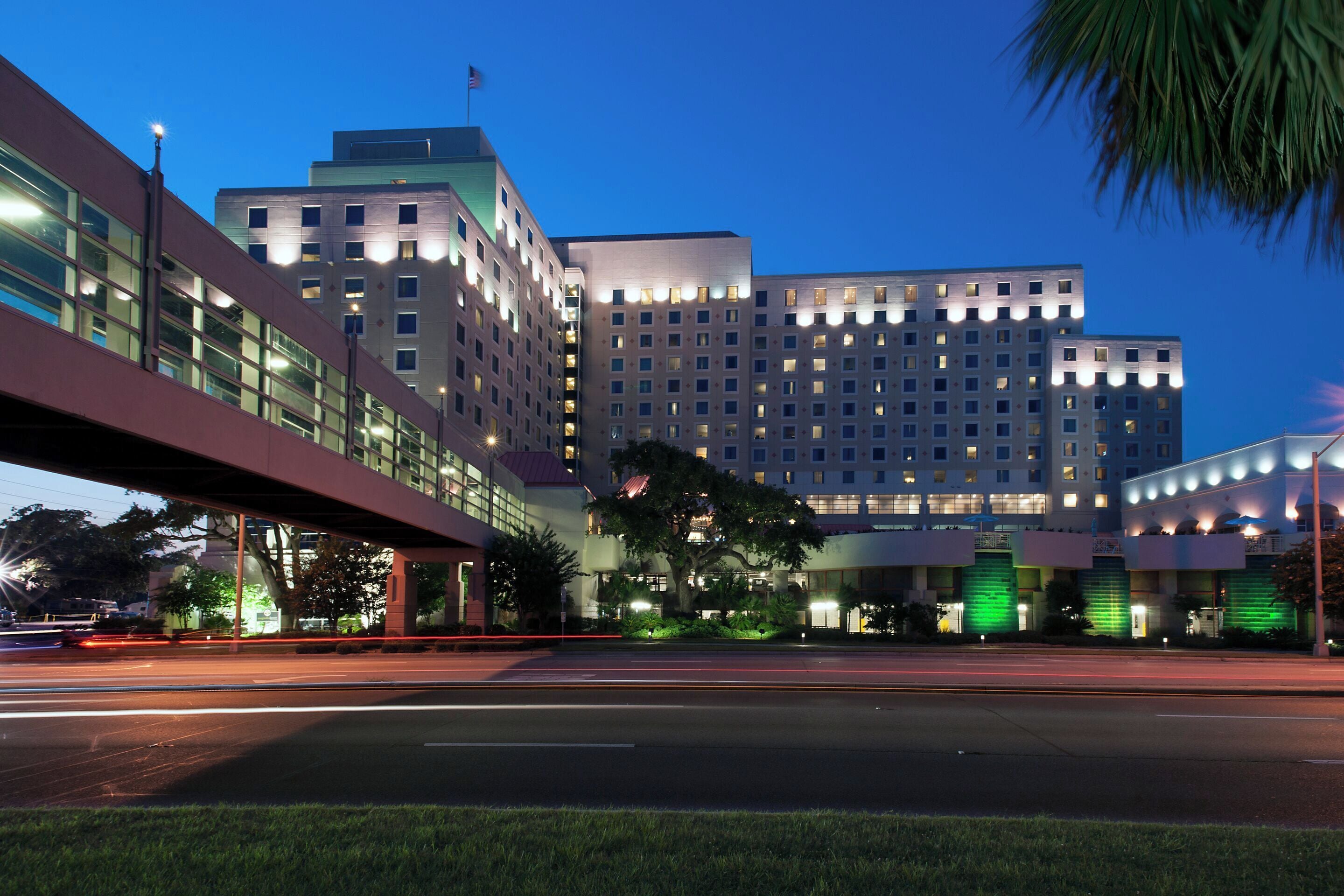 Ein mehrgeschossiges Hotel mit modernem architektonischen Design, das eine markante Eingangshalle und einen Parkplatz bietet.
