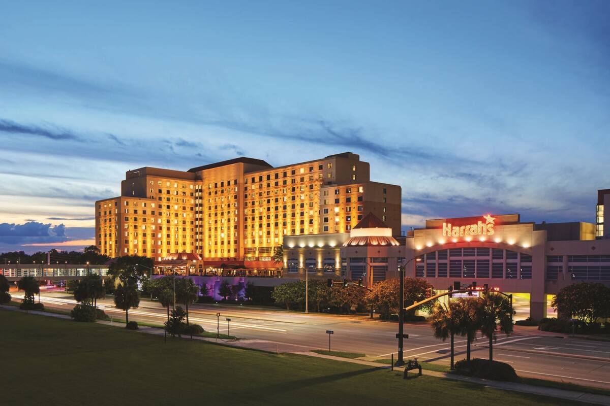 A large, multi-story hotel with a prominent 'Harriss' sign, surrounded by well-maintained lawns and a busy street with moving traffic.