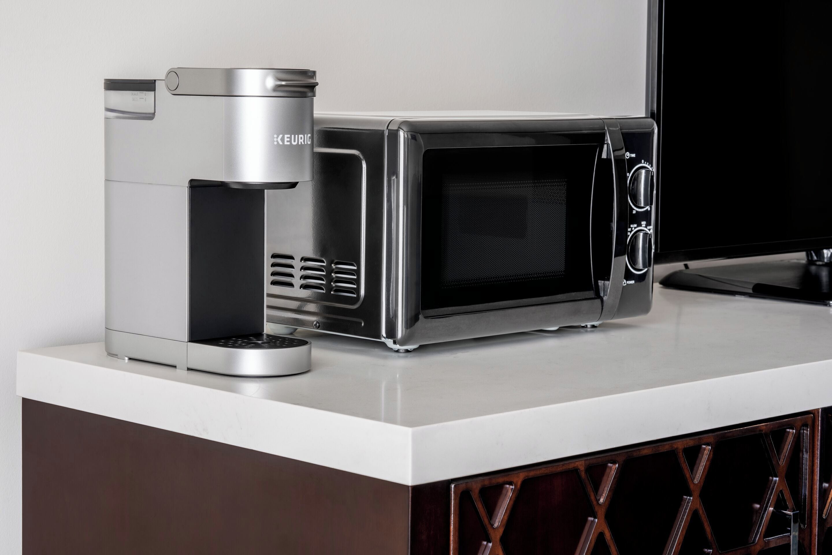 A kitchenette with a coffee maker and microwave on a white countertop.