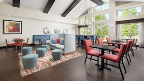 A spacious dining area with high ceilings, modern furniture, and large windows providing natural light.