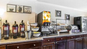 A coffee station with multiple coffee dispensers, a coffee maker, and a fruit display.