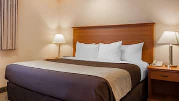 A hotel room with a large bed, two bedside tables, and a wooden headboard.