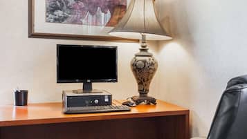 Un escritorio con un monitor de computadora, teclado y una lámpara decorativa.