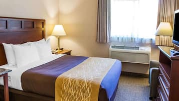 Une chambre d’hôtel avec un grand lit, un bureau avec une lampe, une télévision et un appareil de climatisation.