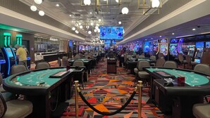 A casino with multiple blackjack tables, slot machines, and a cashier area.