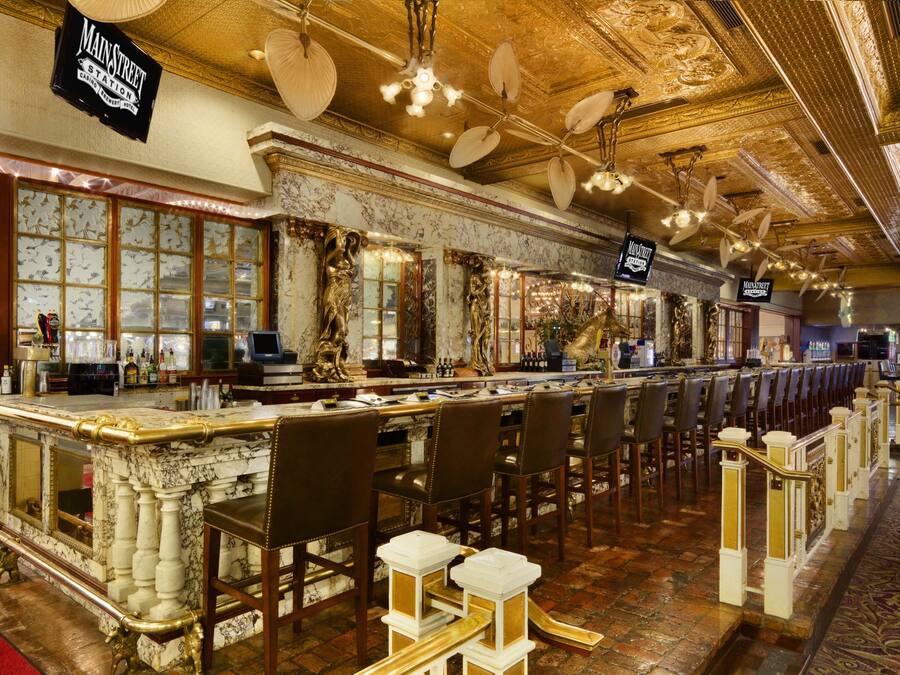 A bar area with marble counters, leather chairs, and a red carpet.