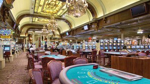 Un casino con múltiples mesas de blackjack, máquinas tragamonedas y una gran lámpara de araña.