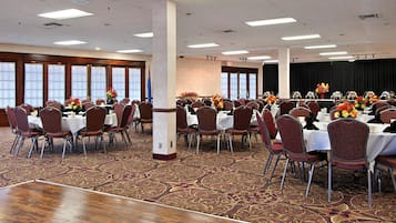 A conference room with multiple tables and chairs, arranged in rows, with floral centerpieces on each table.