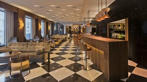 Uma área de bar moderna com piso xadrez, banquetas e balcão.
