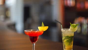 Two cocktails on a bar counter with a blurred background.