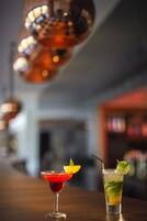 Two cocktails on a bar counter with a blurred background.