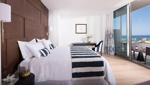 Quarto de hotel com uma cama grande, uma escrivaninha e vista para o oceano.