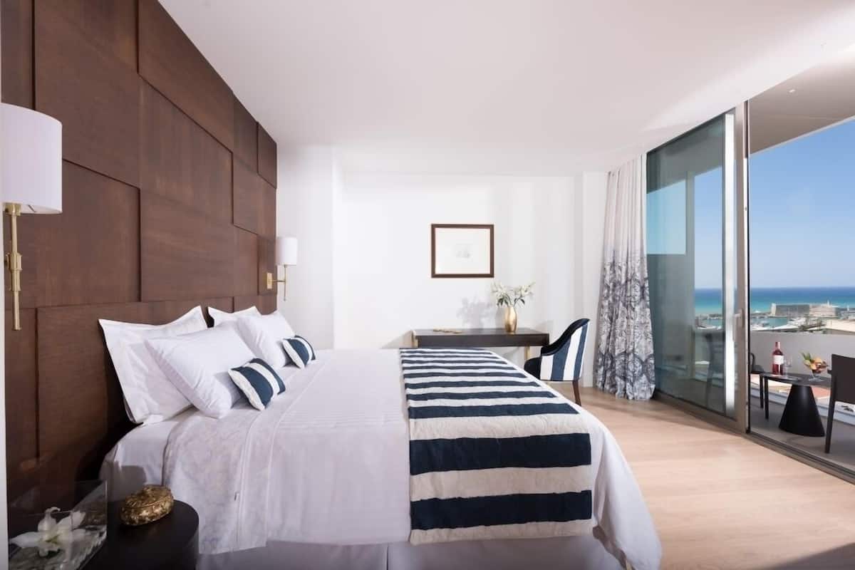 A hotel room with a large bed, a desk, and a view of the ocean.