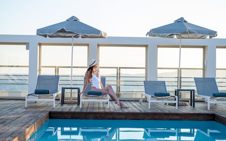 A poolside area with lounge chairs and umbrellas, overlooking a body of water.