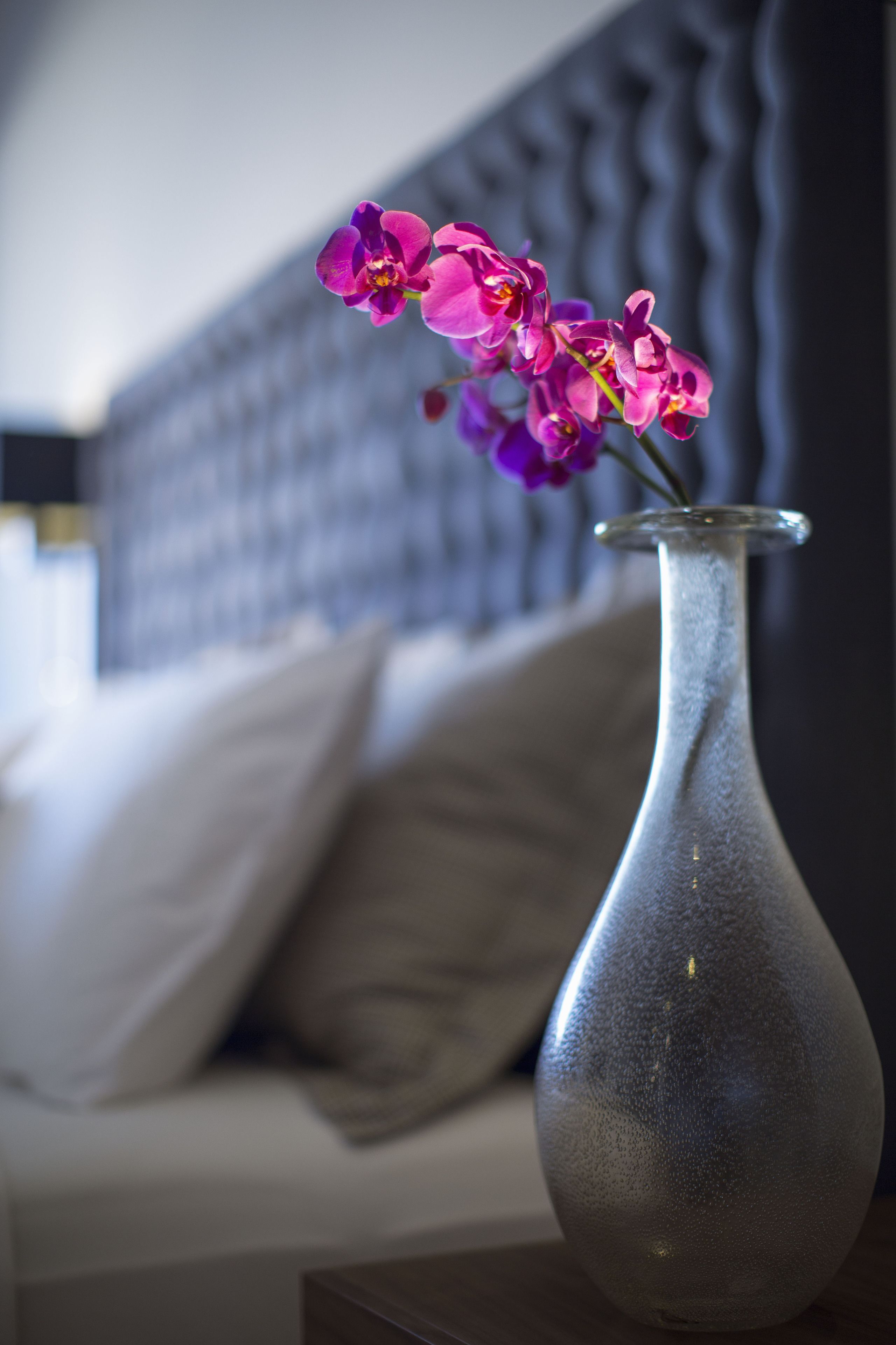 Un vase rempli de fleurs est posé sur une table, à côté d’un canapé.