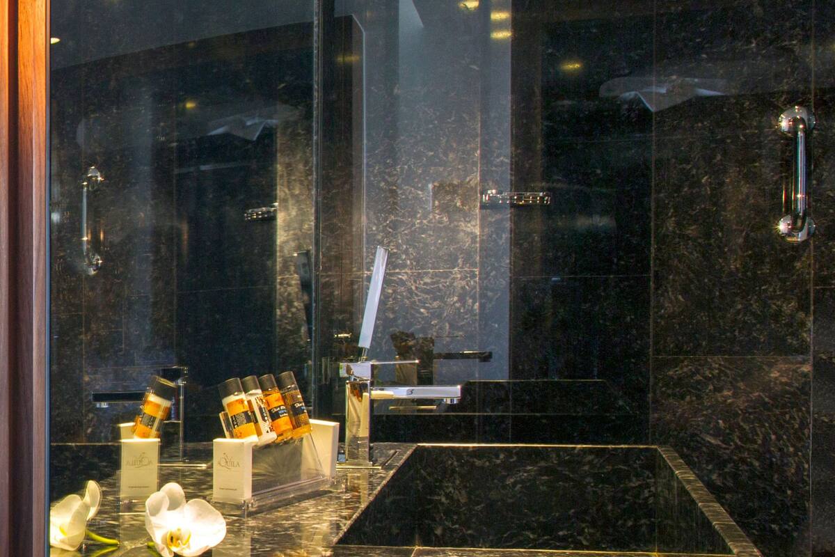 A modern bathroom with a marble sink, a glass shower enclosure, and a towel rack.