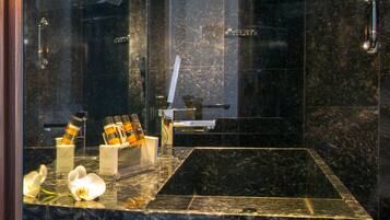 Un baño moderno con lavamanos de mármol, cabina de ducha con mampara de cristal y un perchero para toallas.