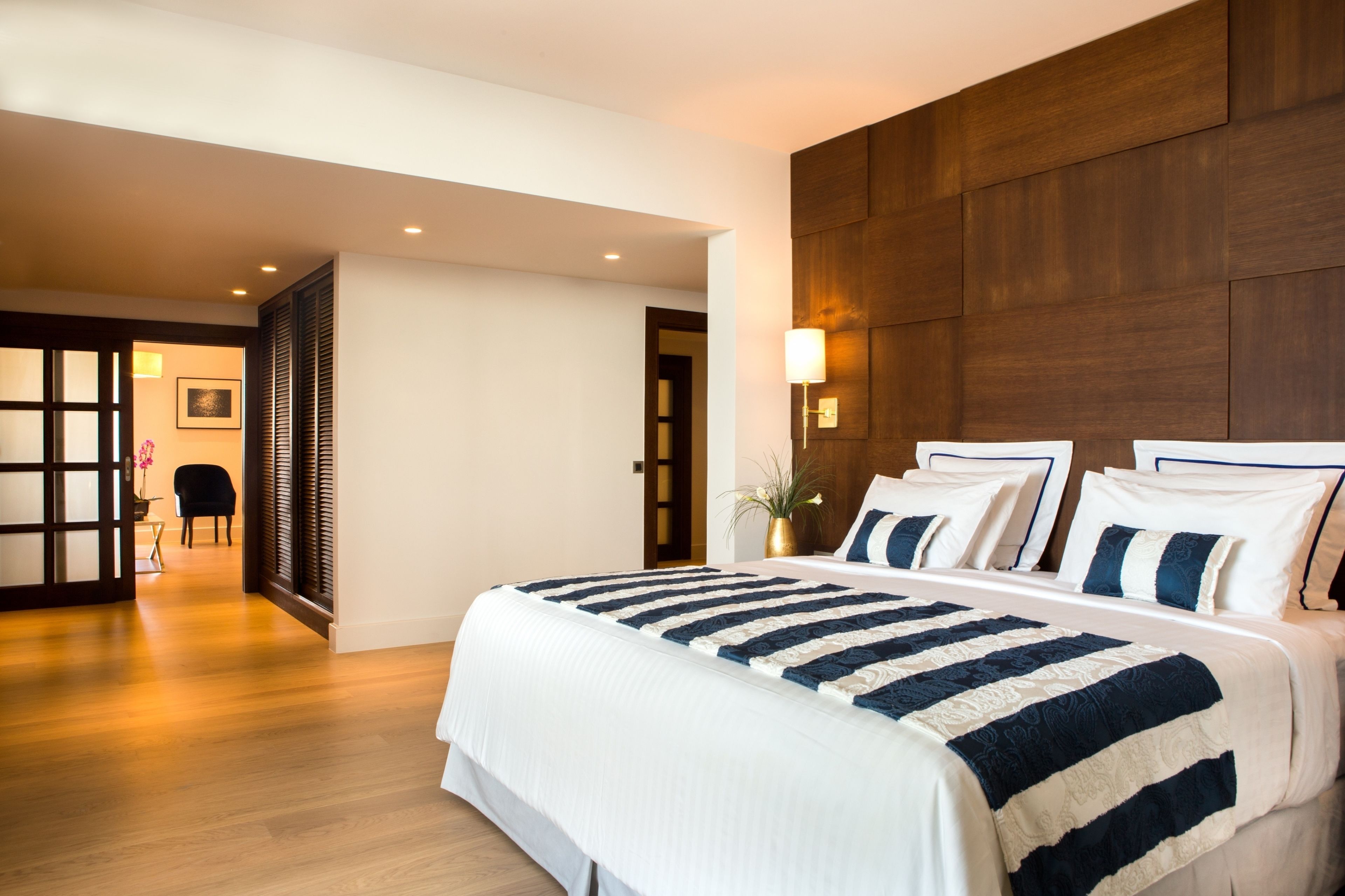 A hotel room with a large bed, wooden headboard, and a view of a traditional Japanese room.