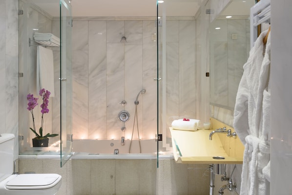A modern bathroom with a glass-enclosed shower, a bathtub, a sink with a mirror, and a toilet. - Aquila Atlantis Hotel (Heraklion)