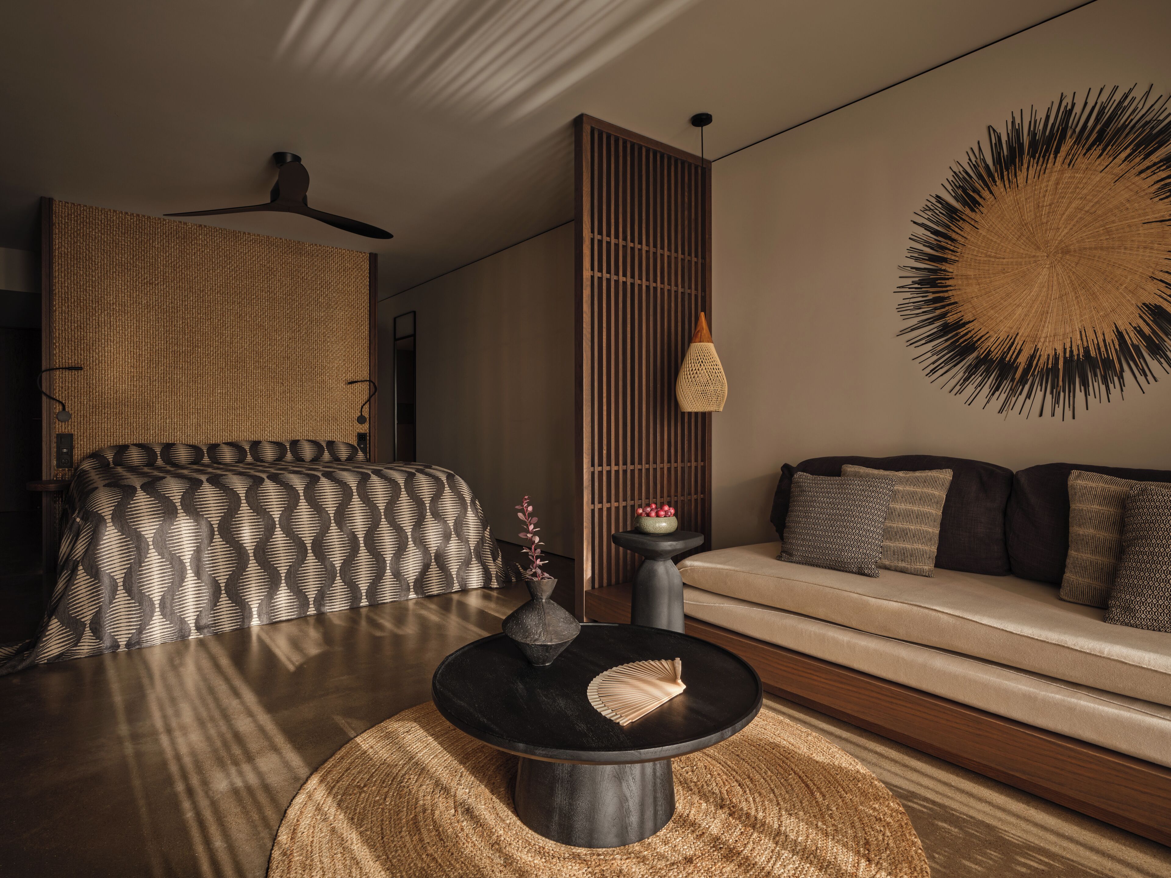 Un dormitorio moderno con cama, sofá, una mesa redonda y un adorno en la pared.