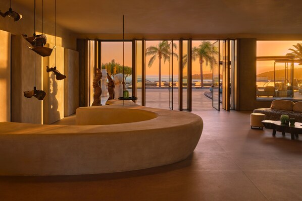 Ein modernes Interieur mit einer runden Sitzecke, großen Fenstern und Blick auf den Strand.