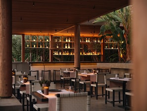 Ein Restaurant mit Tischen und Stühlen, einer Holzbalkendecke und Regalen mit Flaschen.