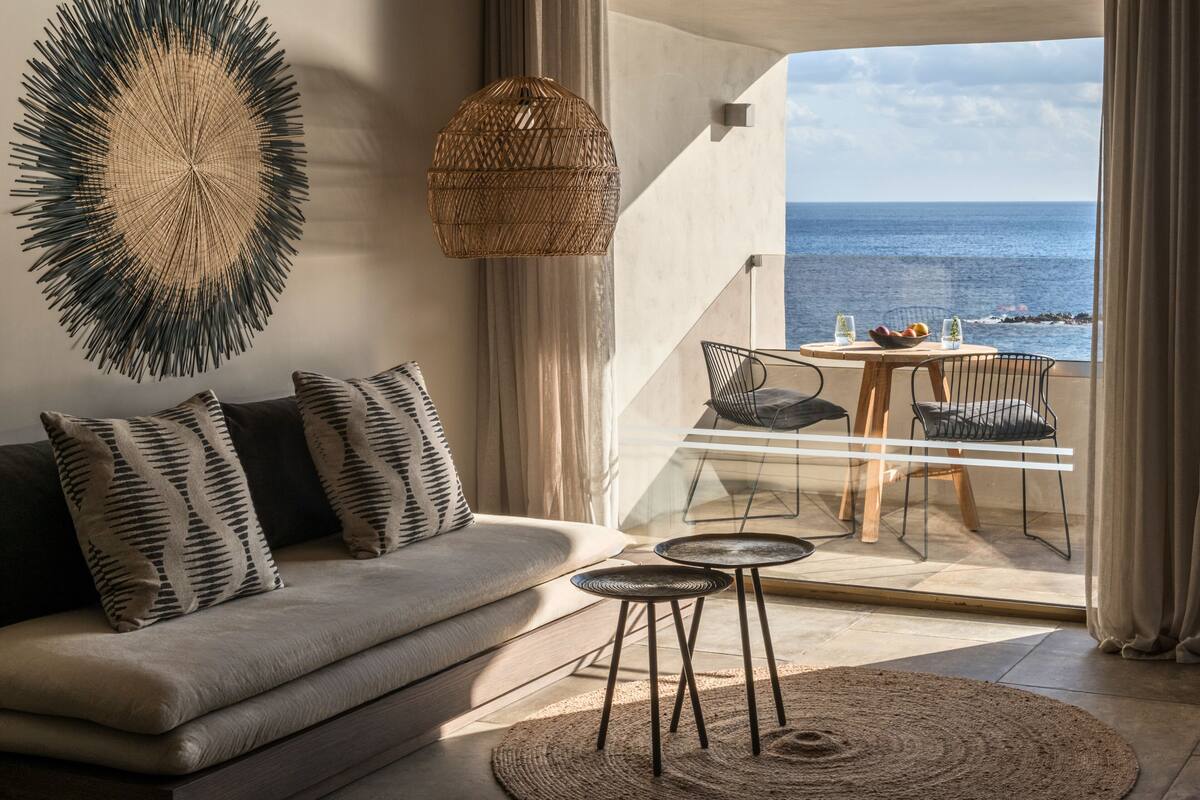 Een moderne woonkamer met een bank, een ronde tafel en uitzicht op zee.