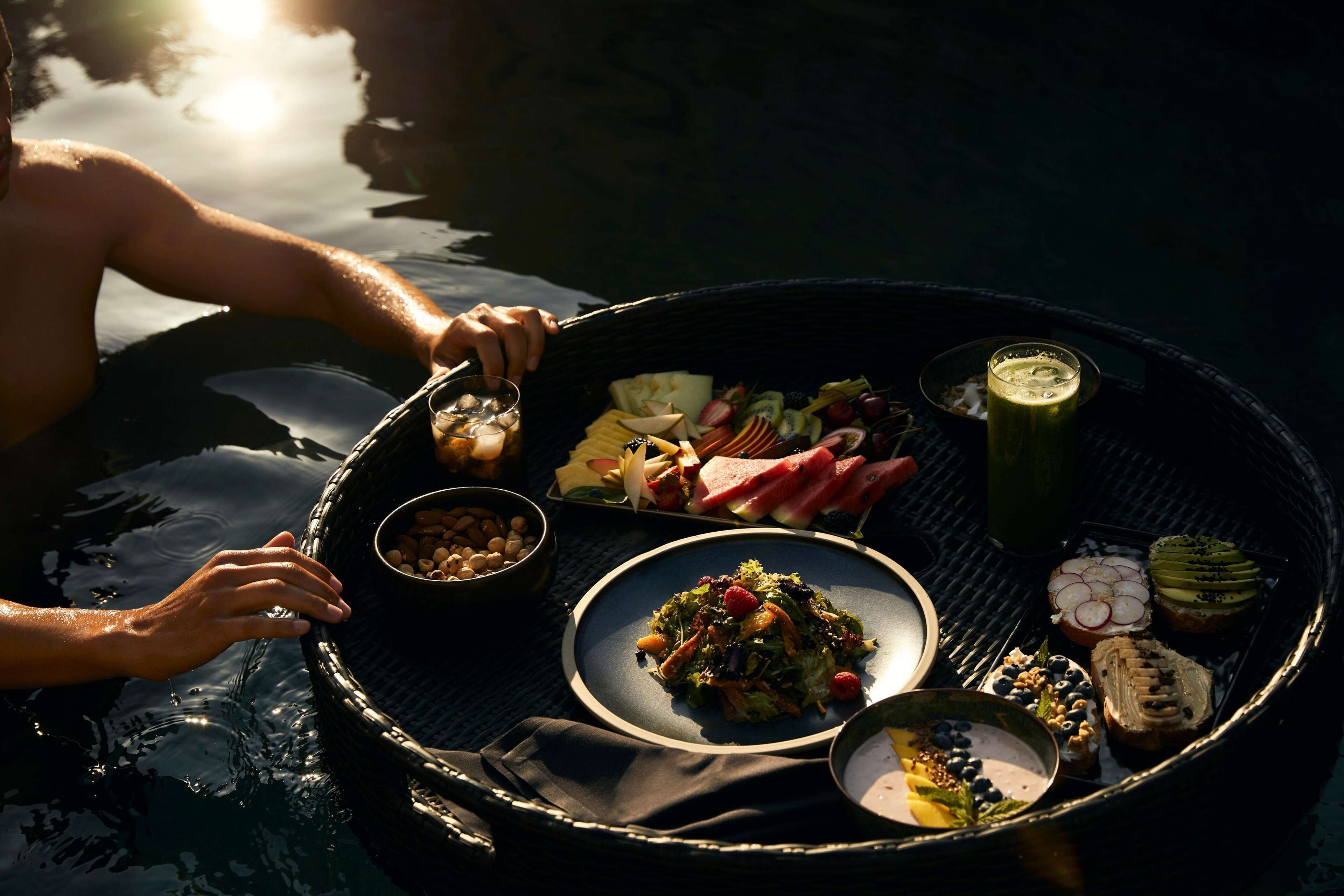 A dining setup by a body of water with a variety of food items and drinks on a tray.
