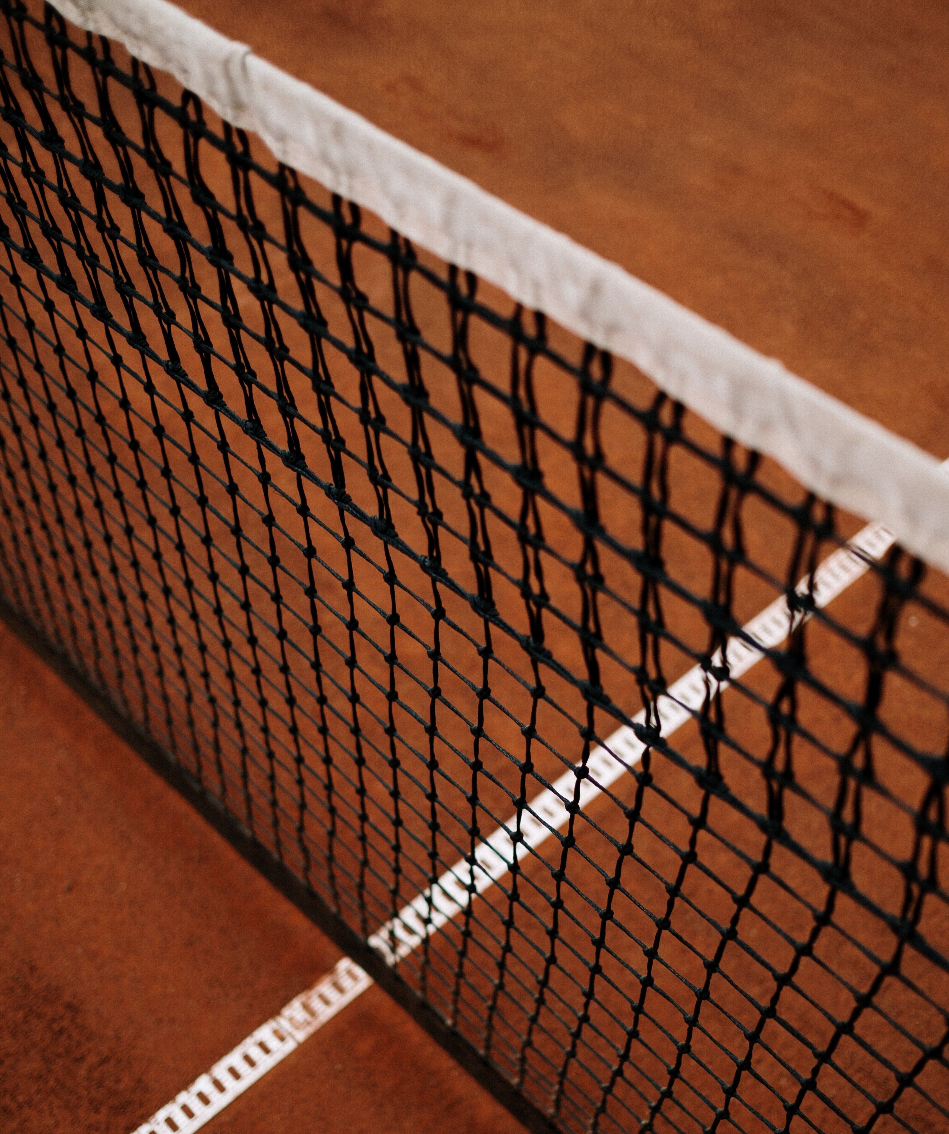 Primer plano de la red de una cancha de tenis, con un diseño blanco y negro y una línea blanca que marca el límite.