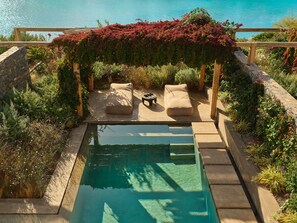Ein Pool mit einer Holzterrasse, zwei beigen Sofas und einem Tisch.