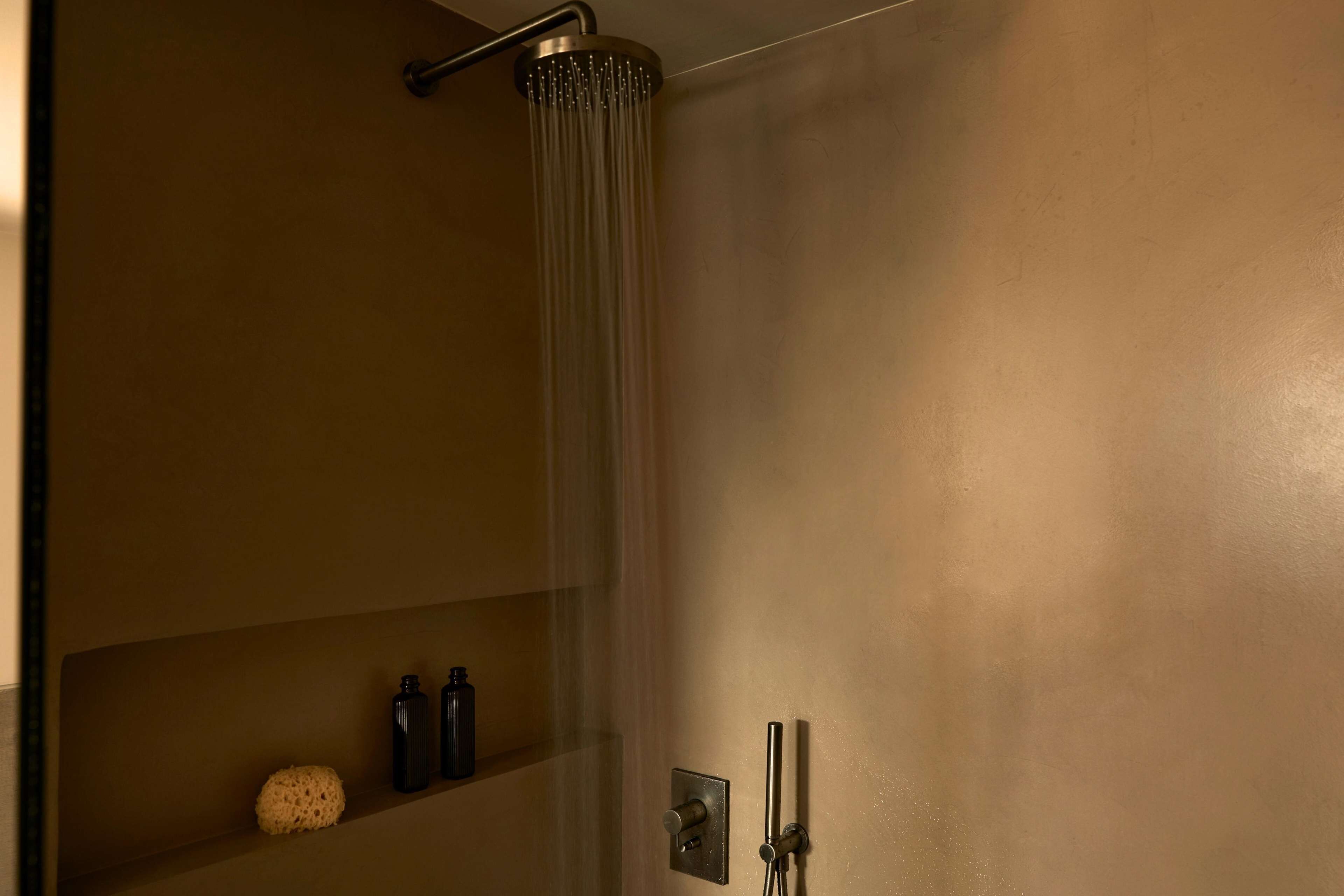A shower with a glass door, a towel rack, and a shelf with toiletries.