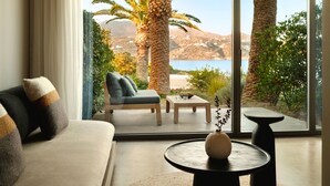 Een moderne woonkamer met een bank, een bijzettafeltje en uitzicht op palmbomen en een wateroppervlak.